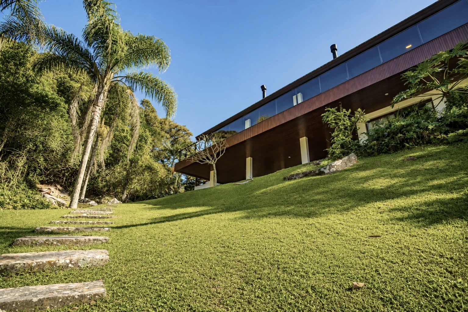 Fachada da residência entre jardins tropicais